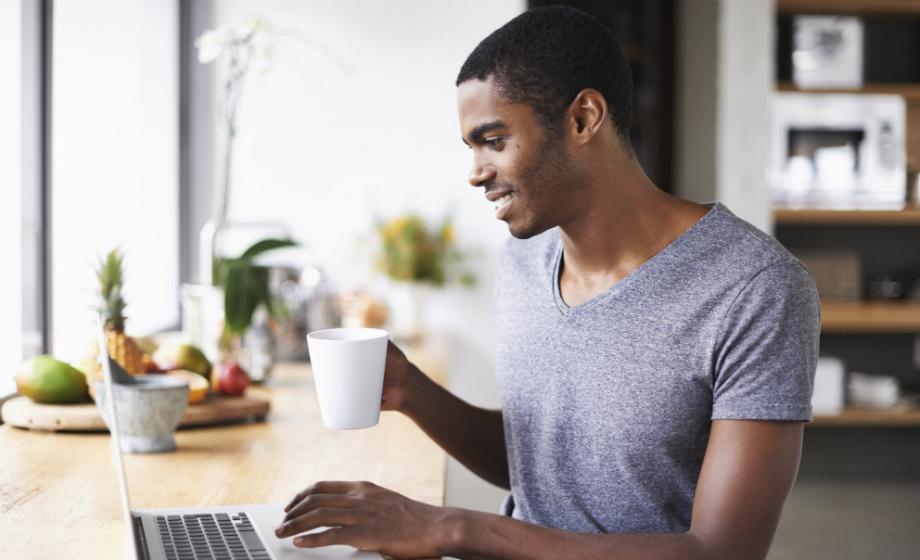 Man on his computer holding a coffe mug