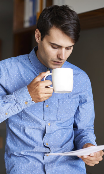 Man drinking coffee and reading a piece of paper